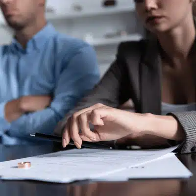 Close-up of divorce paperwork and wedding ring on table during discussion about collaborative divorce vs traditional divorce