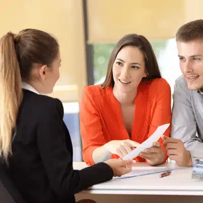 Smiling couple consults attorney, reviewing adoption paperwork and asking questions during office appointment for guidance