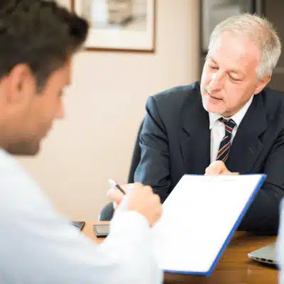 Senior attorney explains documents on clipboard; client listens, wondering what does an adoption lawyer do