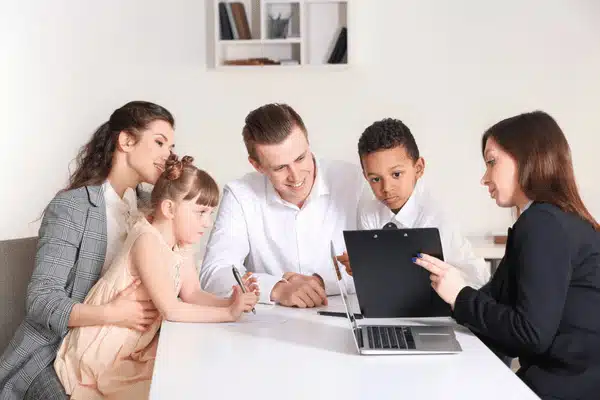 Adoptive family meets attorney, reviewing paperwork together at laptop during supportive adoption consultation in office