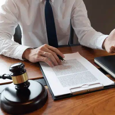 Attorney reviews legal contract on clipboard beside gavel, discussing adoption case details with client today
