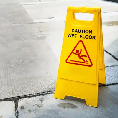 A yellow sign warns pedestrians of a wet floor, relevant to Texas Slip and Fall Laws