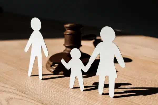 Paper family cutouts stand before judge's gavel, symbolizing child custody decisions in courtrooms and law