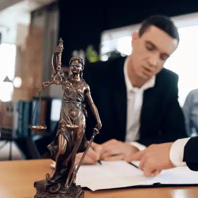 Lawyer consults client beside Lady Justice statue, discussing who can file a wrongful death lawsuit