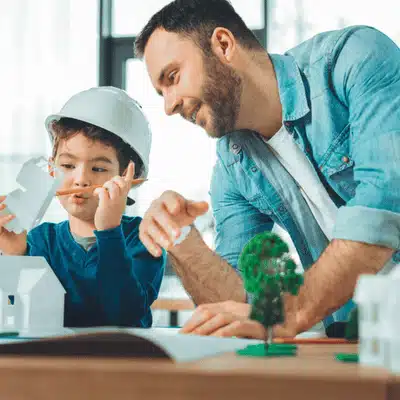 Father guides child building model houses, emphasizing stable home environment considered in custody evaluations processes