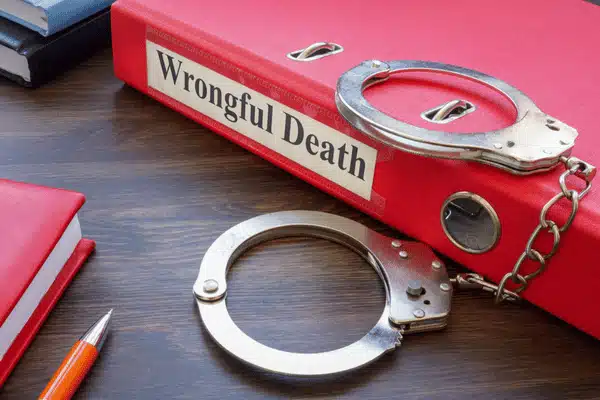 Red binder labeled 'Wrongful Death' with handcuffs on table, symbolizing legal case documentation and evidence