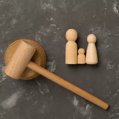 Wooden gavel beside family figurines on gray surface, representing legal decisions affecting parental rights cases